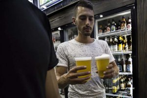 לקוח חנות ביר פוינט מחזיק כוסות בירה צילום: צפריר אביוב (תמונה להמחשה)